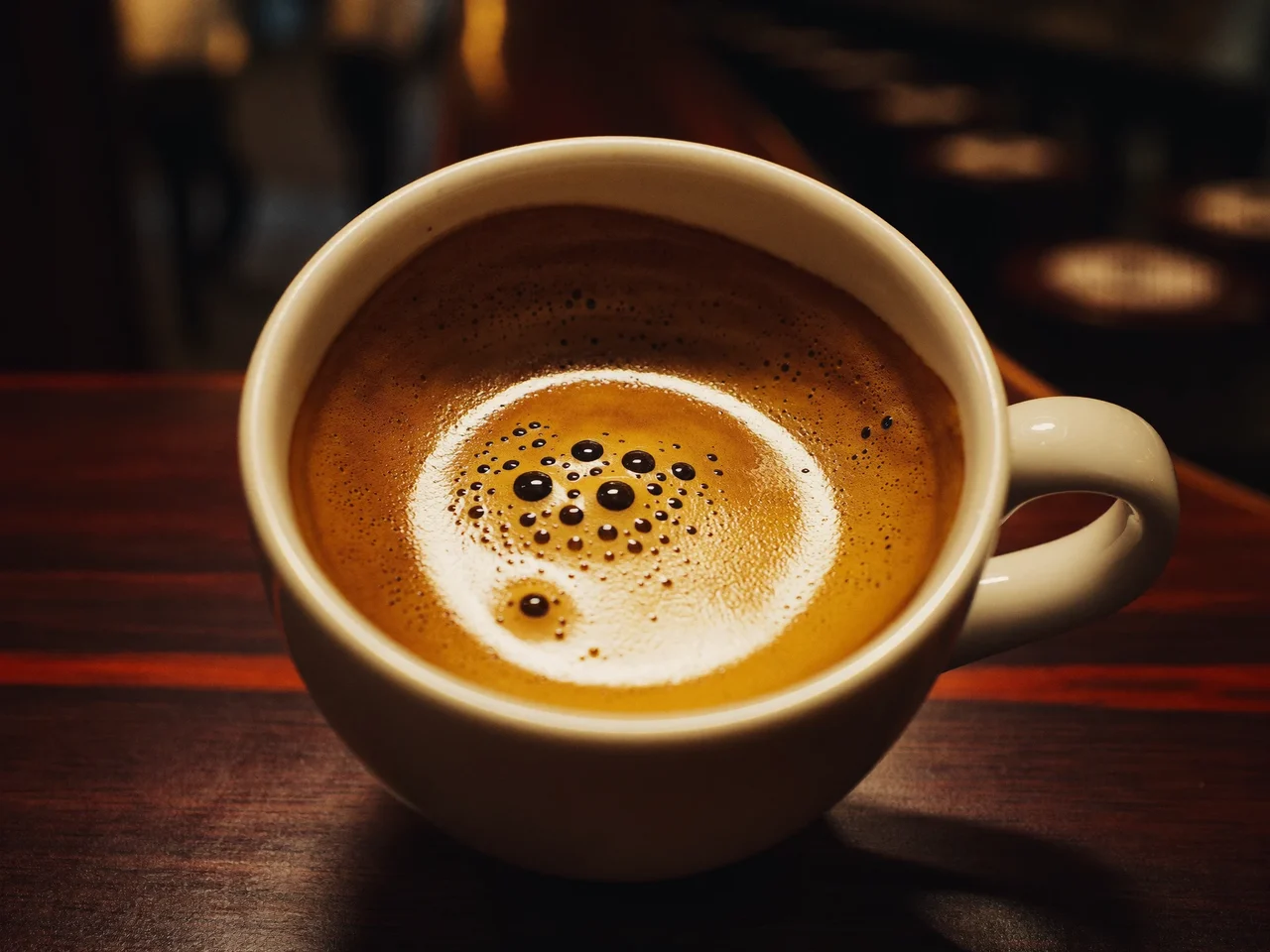 Frisch gezogener Espresso mit goldener Crema in weisser Keramiktasse auf dunklem Holz