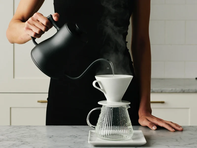 Heisses Wasser wird mit dem Schwanenhalskessel über einen Pour-over-Filter geführt