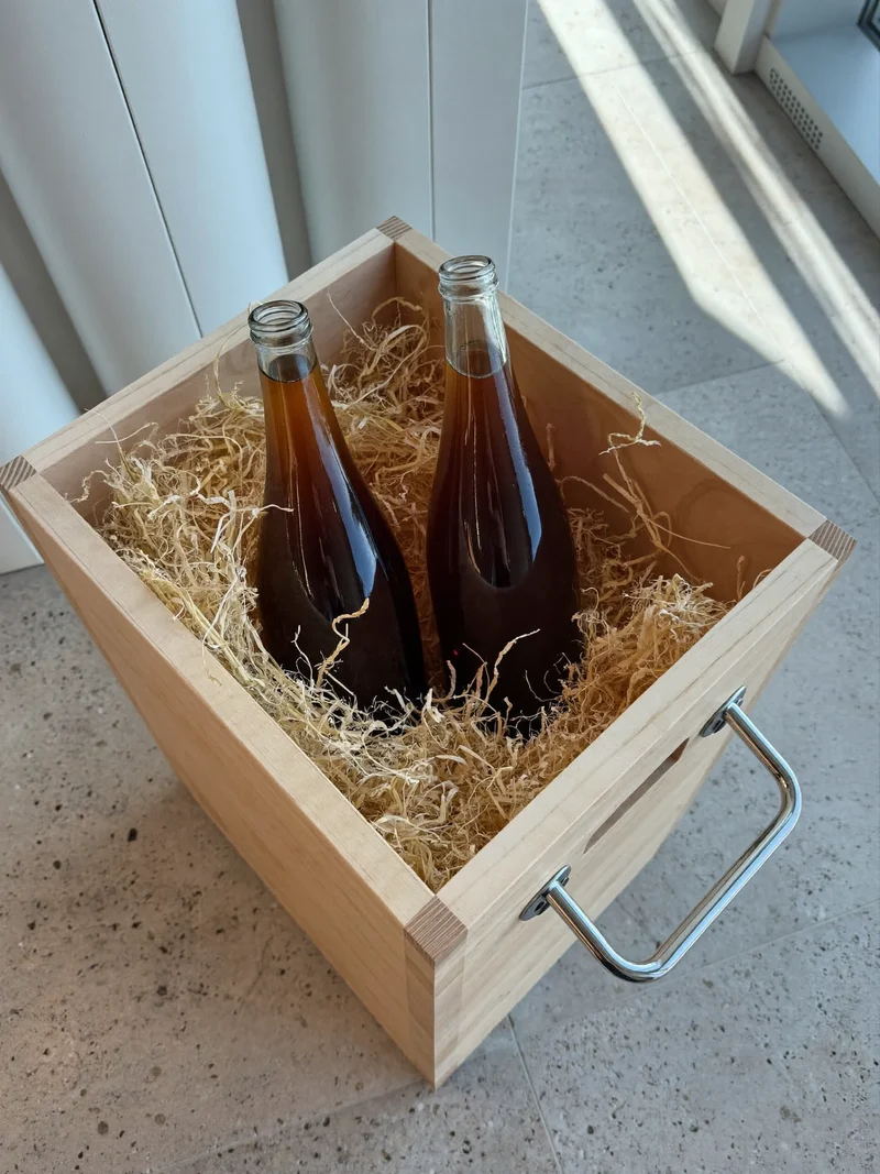 Zwei Cold-Brew-Flaschen in einer Holzkiste mit Strohpolster als Lieferverpackung